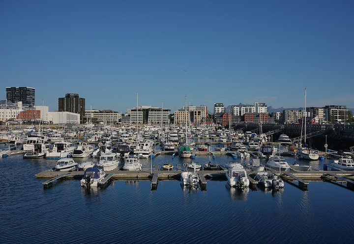 Bateaux et bâtiments en bord de mer dans le port de Bodø avec au-delà des montagnes du nord de la Norvège