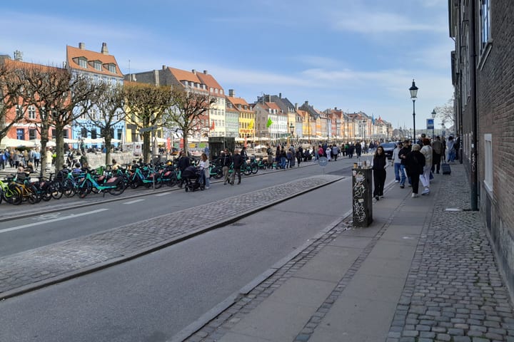 Bunte Gebäude in Nyhavn, Fußgänger und Fahrräder in Kopenhagen, aufgenommen im April 2025