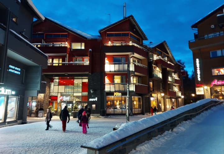 Le centre de Levi avec hôtels, boutiques et skieurs par une soirée enneigée