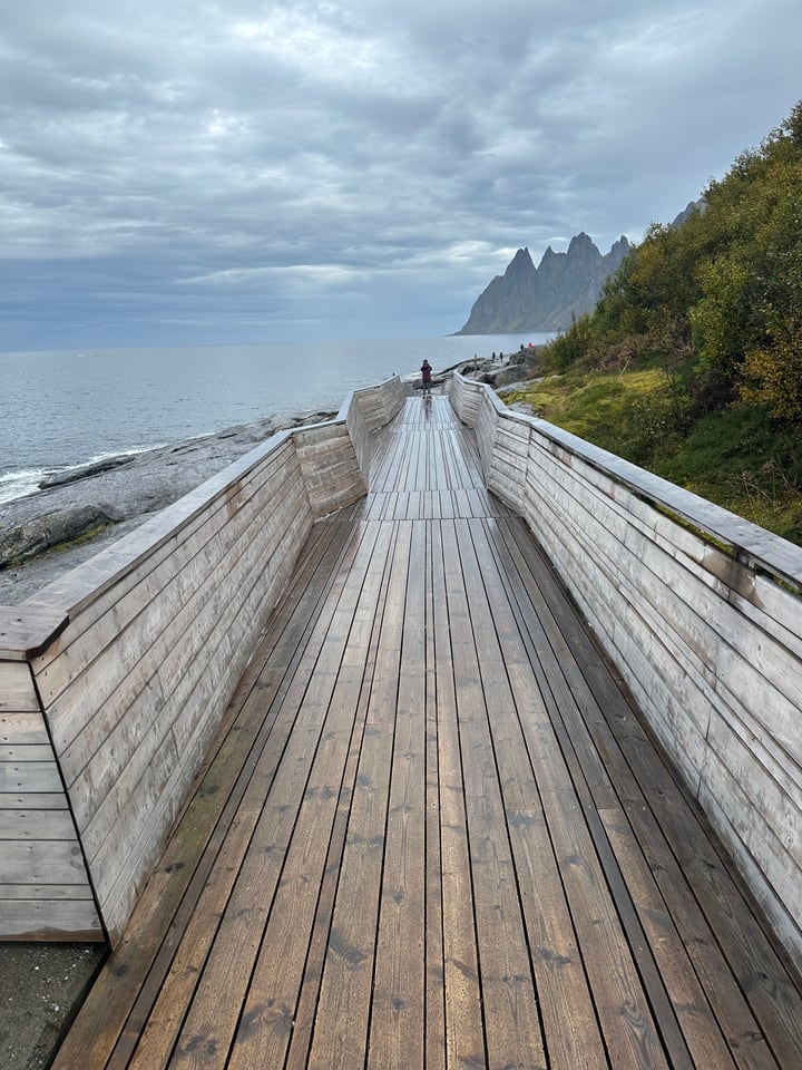 Holzbohlenweg an einer norwegischen Küste unter steilen Bergen