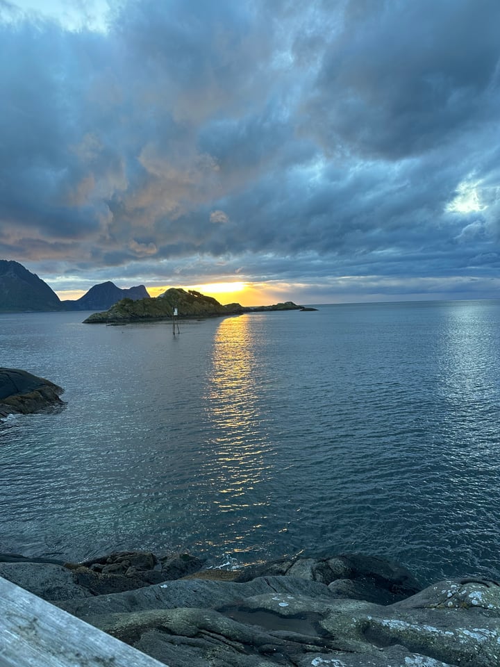 Sonnenuntergang über einer felsigen norwegischen Küste und ruhigem Wasser