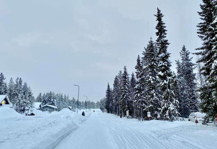 Verschneite Straße und Hütten im Dorf Äkäslompolo unterhalb des Ylläs im Winter